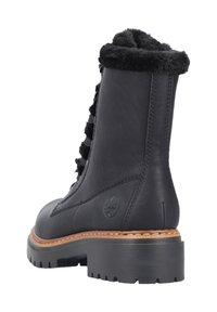 Bottine noire en cuir avec un col en fourrure noire moelleuse, un devant lacé et une semelle en caoutchouc épaisse. Comprend des détails cousus et un logo de la marque.