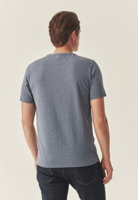 Tričko s krátkým rukávem a kulatým výstřihem v melírované tmavě modré látce. Zadní část má hladkou texturu bez viditelných log nebo vzorů.