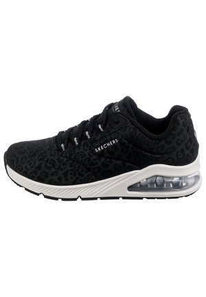 Chaussure de sport noire Skechers avec imprimé léopard subtil, lacets noirs, semelle intermédiaire blanche et semelle à coussin d’air transparente sur fond blanc.