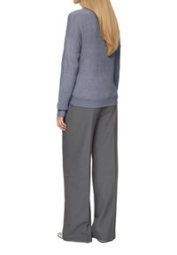 Pull en tricot gris avec un col rond et des poignets côtelés, associé à un pantalon gris ample. Tissu texturé avec un motif subtil.