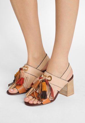 Beżowe sandały na obcasie ze skóry, z zamkniętym tyłem, ozdobione chwostami w kolorach pomarańczowym, czerwonym i brązowym oraz teksturowanym obcasem na klocku przypominającym drewno.