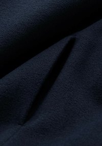 Tessuto di lana blu navy con una superficie morbida e testurizzata, caratterizzato da pieghe sottili e una finitura liscia. Ideale per capispalla o capi su misura.