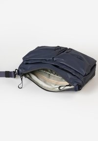 Marineblaue Umhängetasche mit zwei vorderen gepolsterten Taschen und teilweise offenem oberen Reißverschluss, der das hellgraue Innenfutter zeigt.