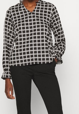 Blusa fluida in bianco e nero con motivo a griglia, scollatura a V e polsini arricciati. Realizzata in tessuto leggero, vestibilità comoda e rilassata.