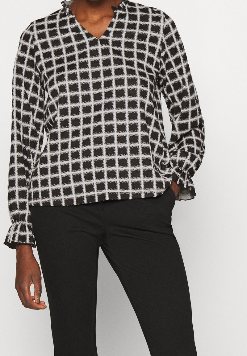 Fließende Bluse in Schwarz-Weiß mit Karomuster, V-Ausschnitt und gerafften Bündchen. Hergestellt aus leichtem Stoff, lockere Passform für optimalen Komfort.