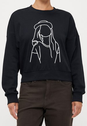 Personne portant un sweat-shirt noir avec un dessin en ligne blanc d'une femme sans visage portant un chapeau sur le devant.