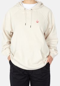 Hoodie de couleur crème avec capuche à cordon, manches à revers, poche avant et petit logo rose sur la poitrine.