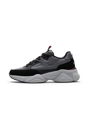 Zwart-grijze FILA sneaker met dikke witte zool, veters aan de voorkant en een bordeaux trek-lus aan hiel en tong, zijaanzicht op witte achtergrond.