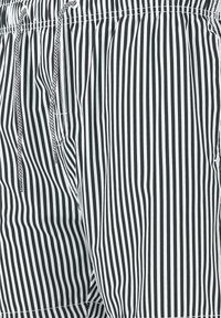 Schwarz-weiße gestreifte Badehosen aus leichtem Material, mit einem elastischen Bund und Kordelzug für eine verstellbare Passform.