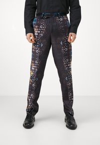 Patterned trousers in a dark fabric featuring colorful butterfly motifs and geometric designs. Tailored fit with a slight sheen and side pockets.