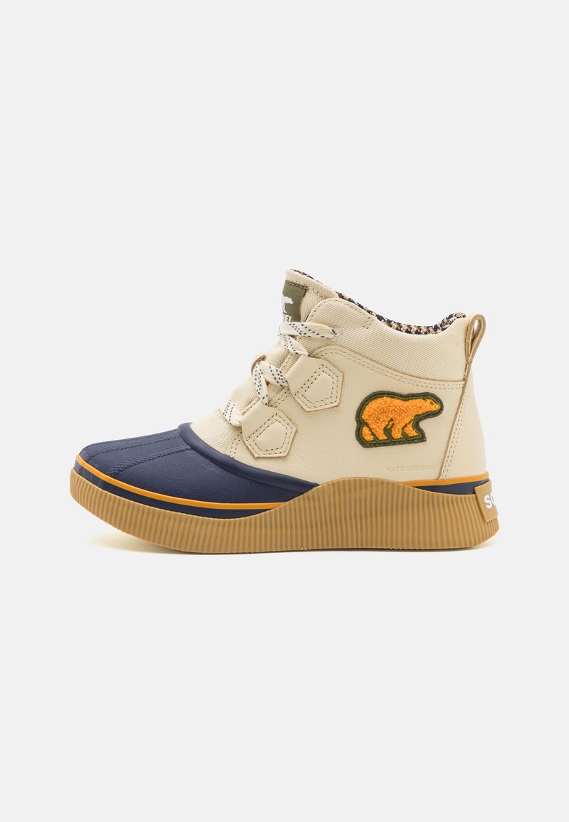 Baskets montantes beige et marine en matériau imperméable, avec une semelle en caoutchouc, des rayures texturées et un logo d'ours sur le côté. Comprend un système de laçage.