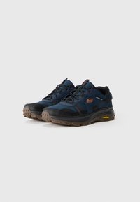 Ciemnoniebieskie buty trekkingowe z czarnymi akcentami, wyściełanym językiem i kołnierzem, teksturowaną gumową podeszwą, z wyraźnym logo i wzmocnionymi detalami.