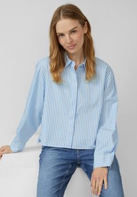 Lichtblauw gestreept overhemd met lange mouwen, losse pasvorm en met een kraag, gecombineerd met donkerblauwe jeans.