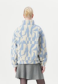 Fleece pullover met hoge kraag, voorzien van een lichtblauw en crèmekleurig geometrisch patroon. Dikke, gestructureerde stof met een comfortabele pasvorm.