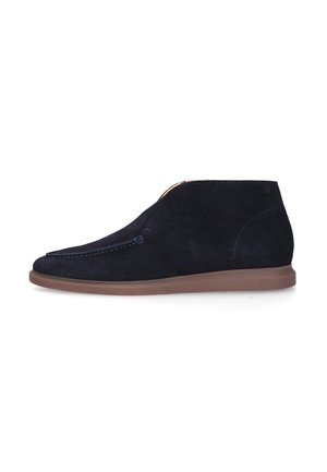 Chaussure montante en daim bleu foncé avec semelle plate marron, bout arrondi et couture latérale visible sur fond blanc.