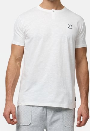 T-shirt blanc à manches courtes en tissu léger, avec un col henley et un bouton, ainsi qu'un petit emblème sur la poitrine gauche.