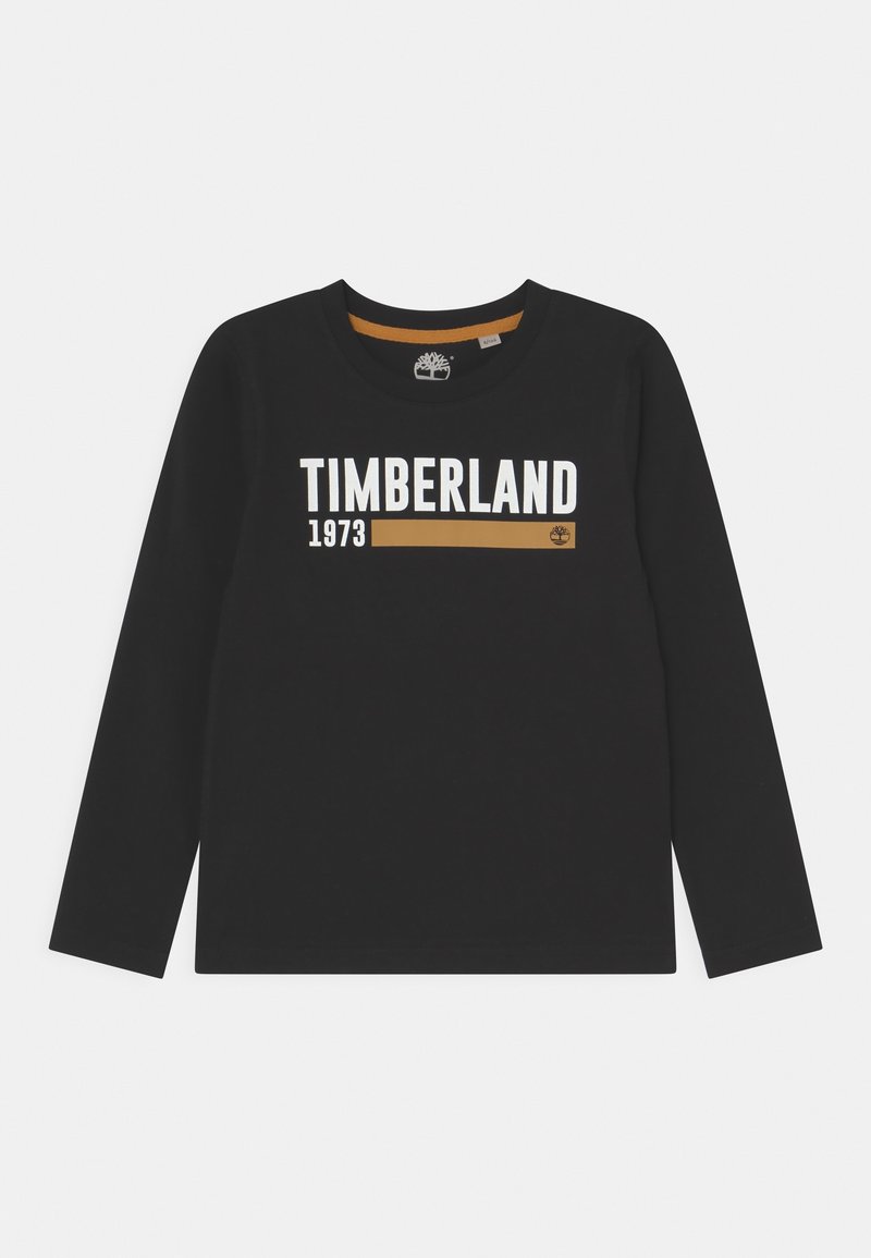 Černé dlouhé rukávy tričko vyrobené z bavlny. Na přední straně má nápis "TIMBERLAND" v bílé a zlaté barvě s rokem "1973." Klasický kulatý výstřih.