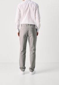 Gray cotton pants with a slim fit, featuring two back pockets and a button detail, paired with a white button-up shirt.