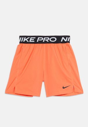 Svetlo oranžové športové šortky s čiernym elastickým pásom Nike Pro a malým čiernym logom Nike na ľavom okraji nohavice.