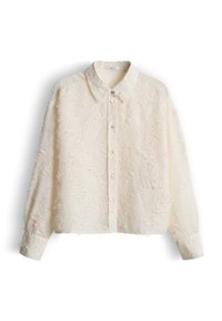 Camicia beige corta con bottoni, con superficie testurizzata e sfrangiata. Presenta un colletto a punta e maniche lunghe con polsini abbottonati.