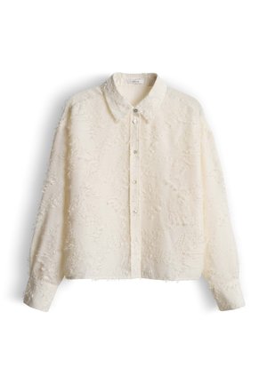 Afgekort beige overhemd met knopen en een gestructureerd, rafelig oppervlak. Voorzien van een puntige kraag en lange mouwen met knoopmanchetten.