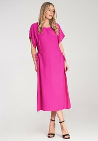 Rosa, fließendes Maxikleid mit kurzen Ärmeln, seitlichen Bändern und einem einfachen runden Halsausschnitt. Weicher Stoff und lockere Passform.