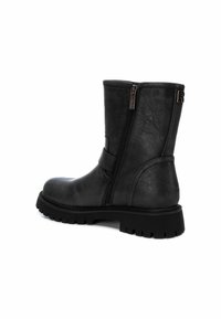 Botín negro de cuero hasta el tobillo con cremallera lateral, cuello acolchado y suela de goma texturizada con prominentes relieves para mayor tracción.