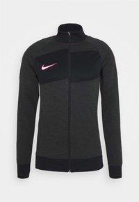 Dunkelgraue und schwarze Nike-Jacke mit durchgehendem Reißverschluss, hohem Kragen, langen Ärmeln und pinkem Nike-Swoosh auf der linken Brust.