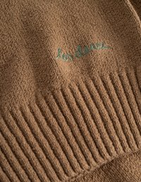 Καφέ υφαντό ύφασμα με ριγέ σχέδιο στο κάτω μέρος. Διαθέτει πράσινη καλλιγραφική κεντημένη επιγραφή που αναγράφει "les den" κοντά στο κέντρο.