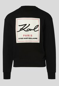 Sudadera negra de manga larga con un dobladillo ajustado. Presenta un gran cuadro gráfico blanco con texto en cursiva negra y acentos rojos.
