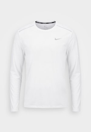 Biała koszulka do biegania Nike z długim rękawem, dekoltem typu crewneck i małym szarym logo Nike po lewej stronie klatki piersiowej.
