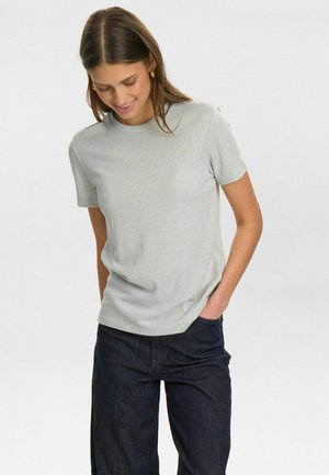 T-shirt court gris clair à manches courtes avec un col rond et un tissu texturé. Associé à un jean foncé, ajustement subtil soulignant la silhouette.