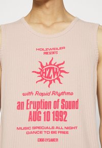Sleeveless ribbed pink top with red text promoting "Holzweiler presents an Eruption of Sound Aug 10 1992" and music event details.