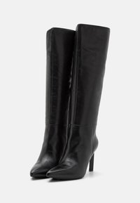 Bottes noires en cuir montantes avec un bout pointu, un design épuré, une texture lisse et un talon aiguille haut.