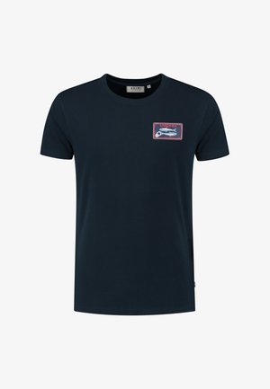 Tumši zila kokvilnas T-krekls ar īsām piedurknēm, kura kreisajā krūtī ir taisnstūrveida "SARDINES" grafiskais motīvs ar zivs dizainu.