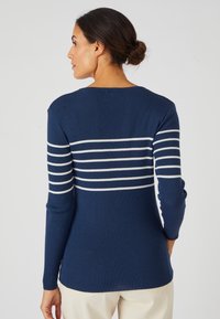 marineblauwe geribde trui met witte horizontale strepen op de rug en armen. Aansluitende lange mouwen en een ronde halslijn.