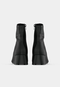 Μαύρες γόβες με ψηλό τακούνι και αστράγαλο με ομαλή, ματ υφή και πλαϊνούς φερμουάρ, που διαθέτουν στρογγυλή μύτη και σχέδιο χονδρού τακουνιού.