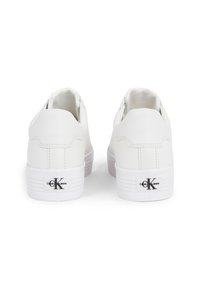 Baskets en cuir blanc à forme arrondie, semelle en caoutchouc texturée, et languette de talon marquée avec le logo en noir.