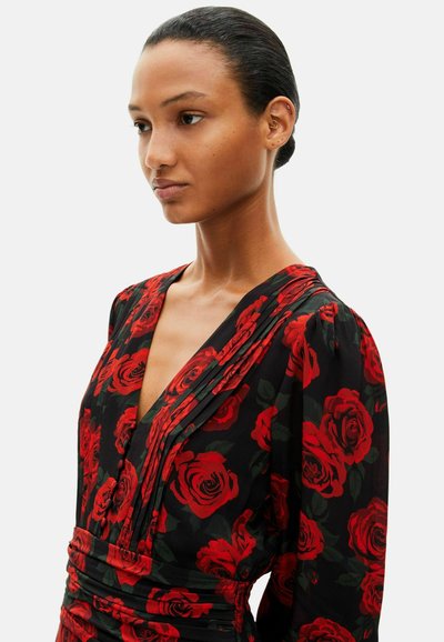 Dress featuring a deep V-neckline, long sleeves, and a fitted waist. Black fabric with a red rose pattern and pleated design details.