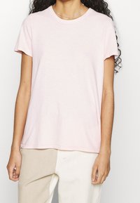 Light pink cotton t-shirt with short sleeves, a round neckline, and a relaxed fit. Smooth texture, no visible patterns or embellishments.