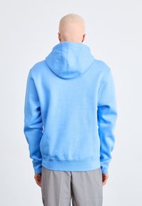 Světle modrá mikina s kapucí, přední klokaní kapsou, žebrovanými manžetami a lemem. Měkká tkanina, nastavitelná kapuce a hladká textura.