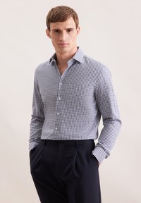 Niebieska i biała koszula z długim rękawem, dopasowany krój, miękka tekstura, lekki kołnierzyk, zestawiona z ciemnymi, dopasowanymi spodniami.