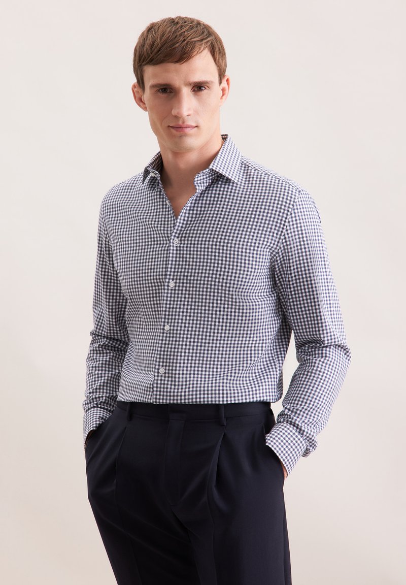 Niebieska i biała koszula z długim rękawem, dopasowany krój, miękka tekstura, lekki kołnierzyk, zestawiona z ciemnymi, dopasowanymi spodniami.