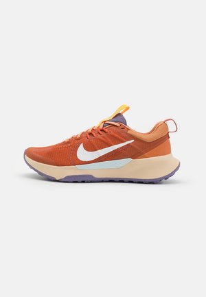 Orange og beige Nike løbesko med hvide swoosh, lilla sål og gul tungeflap, vist i sideprofil på hvid baggrund.