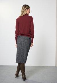 Maroon knit sweater and gray plaid pencil skirt, paired with brown knee-high boots. Smooth texture, fitted design, and subtle detailing.