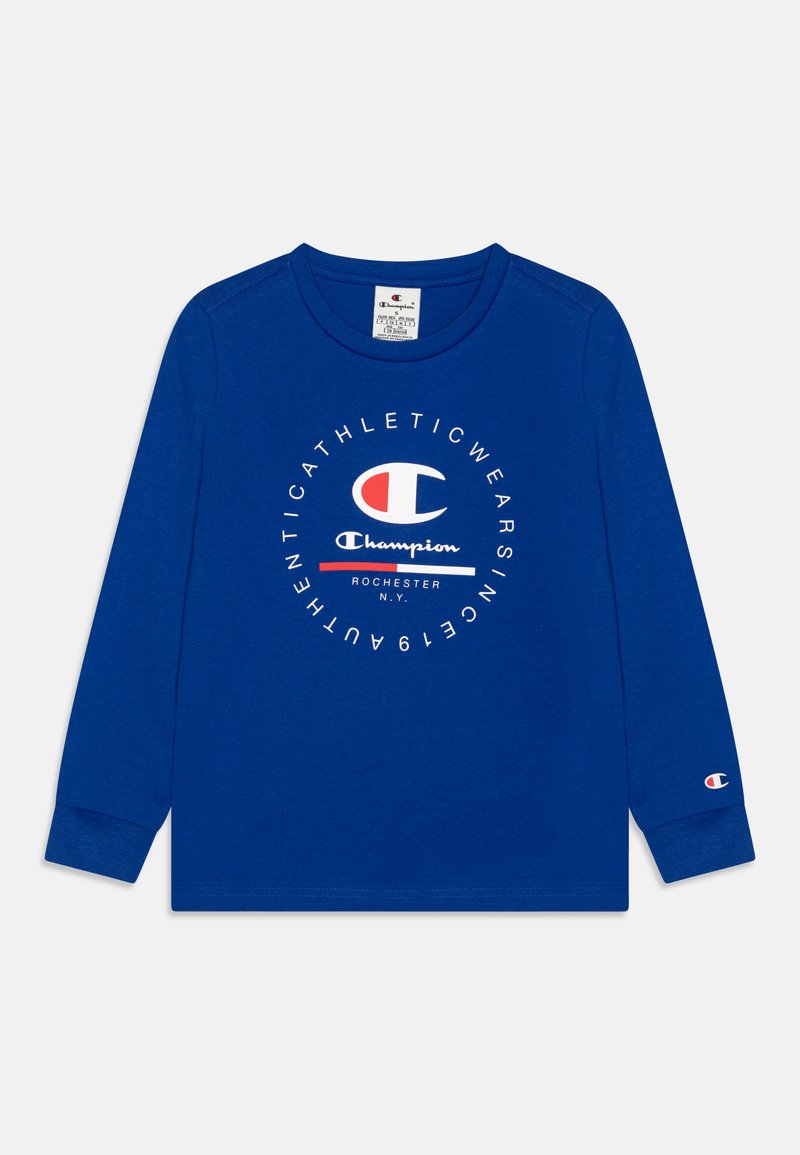 Camiseta de manga larga en algodón azul con un logo circular de Champion en blanco y rojo. Presenta un cuello redondo y puños acanalados.