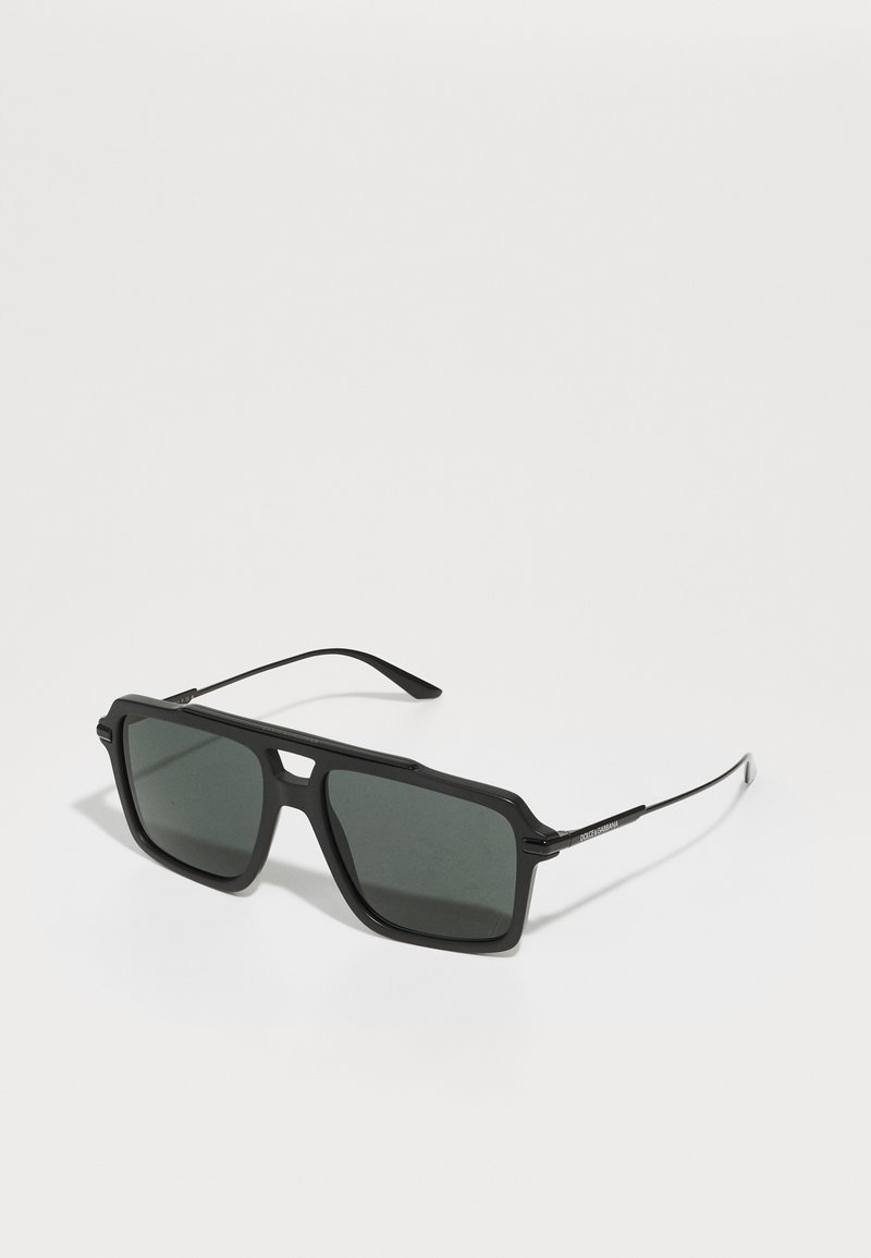 Ochelari de soare negri cu lentile mari pătrate, din plastic cu accente metalice. Au brațe elegante și lentile cu gradație întunecată.