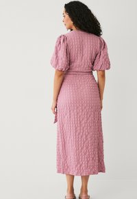 Rosa texturiertes Midikleid mit Puffärmeln und gebundenem Taillengürtel, das ein Karomuster und eine lässige Passform aufweist. Glattes Material mit einem subtilen Glanz.