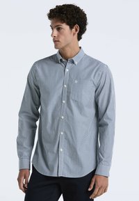 Overhemd met knopen in marineblauw en witte strepen, met een opstaande kraag, lange mouwen en een borstzak met logo-borduring.