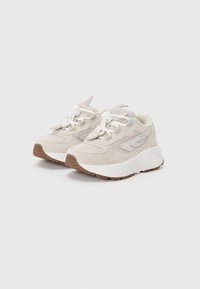 Beige mesh- og suede-sneakers med en tykk hvit mellomsåle, gummisåle og elastiske lisser. Har en teksturert overdel og hæltab.